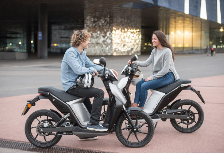 duas pessoas a falar enquanto usam as suas scooter torrot